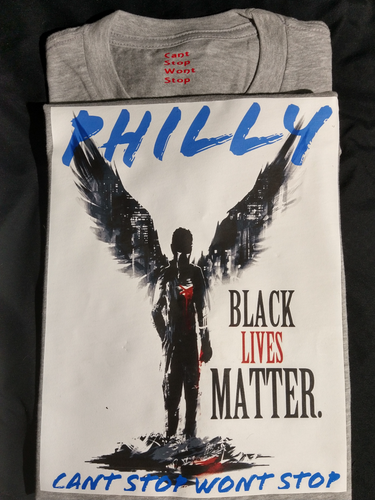 Black angel holding heart in hand, black lives matter written on side of angel, Philly written in blue letters on top of angel, cant stop wont stop written across the bottom of angel written in blue letters,white background on grey shirt with cant stop wont stop printed in small red letters in tag area